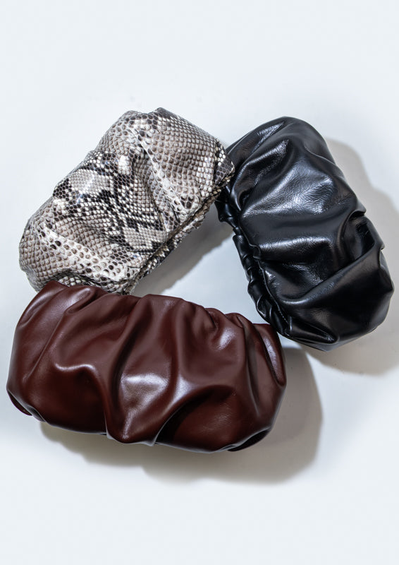 Three leather clutches in snake print, Bordeaux, and black on a white background